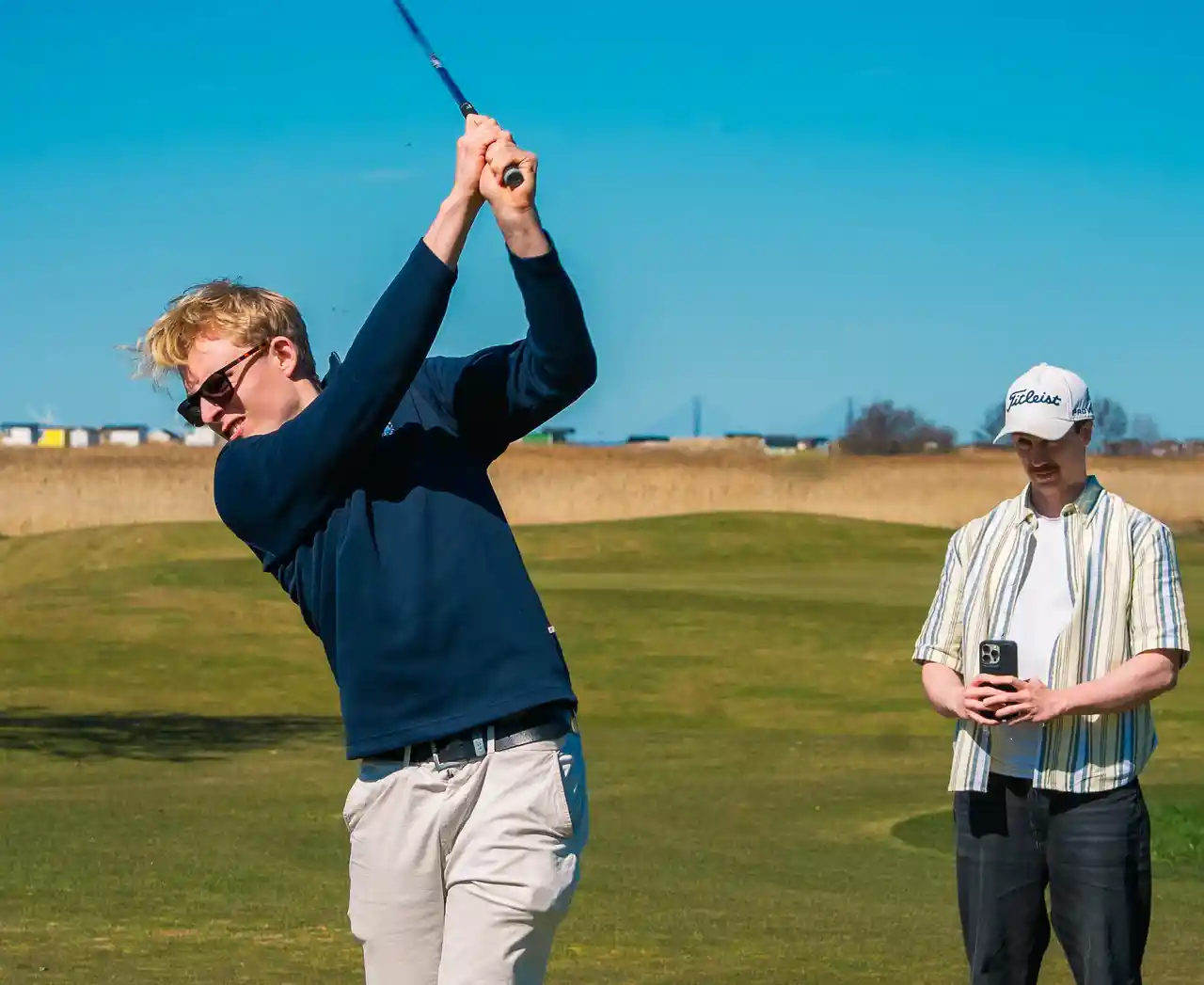 A golfer mid-swing on a links course, Flasterbo Golfklubb (Flasterbo GK)