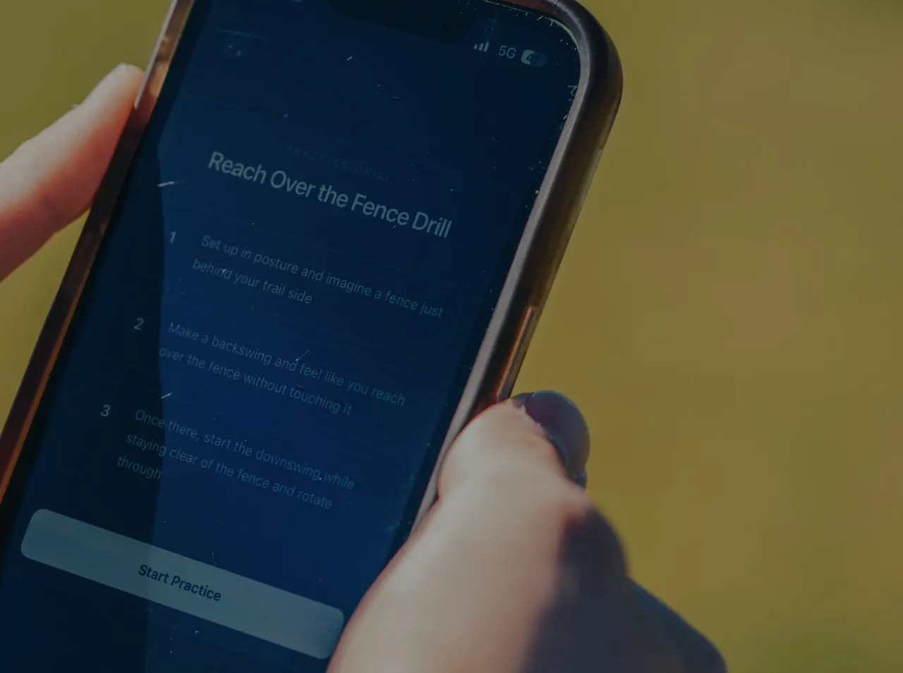 A golfer holding a phone showing a TrueSwing practice drill with step-by-step instructions